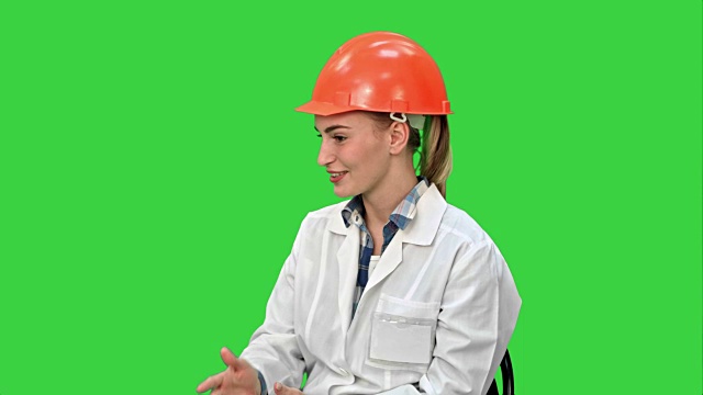女工程师戴着安全帽，坐在绿色屏幕上聊天视频素材