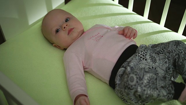 上侧视图可爱的婴儿在粉红色的布躺在床上和移动的手和腿视频下载