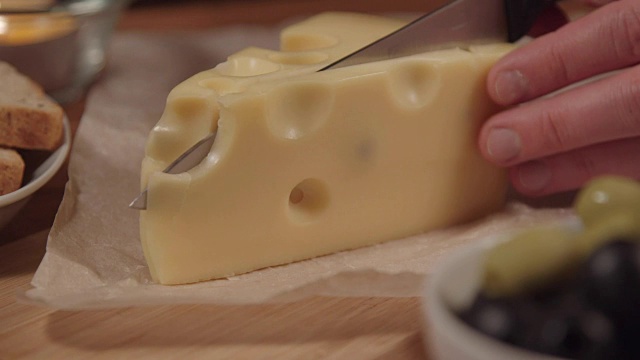 在木板上切奶酪的女人。女人切起司。视频下载