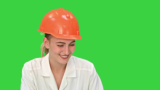 年轻的女建筑工程师微笑着与笔记本电脑在绿色屏幕上进行视频会议，Chroma Key视频素材
