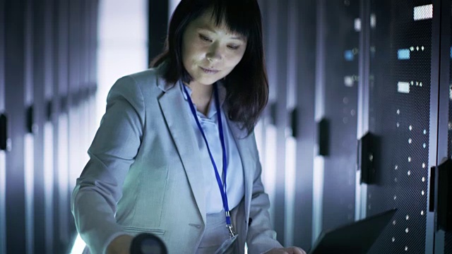 亚洲女性IT工程师工作在一个应急车笔记本电脑，她扫描硬盘。她在满是机架服务器的大数据中心。视频素材