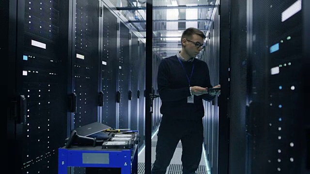 服务器工程师更换机架服务器开放式机柜中的硬盘。他在大数据中心工作。视频素材