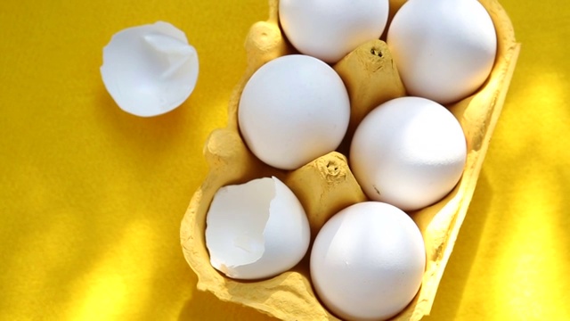 6个鸡蛋装在盒子里，放在旋转的黄色盘子上视频素材