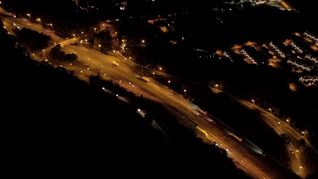 航拍:汽车在高速公路上行驶，经过大城市的郊区城镇视频素材