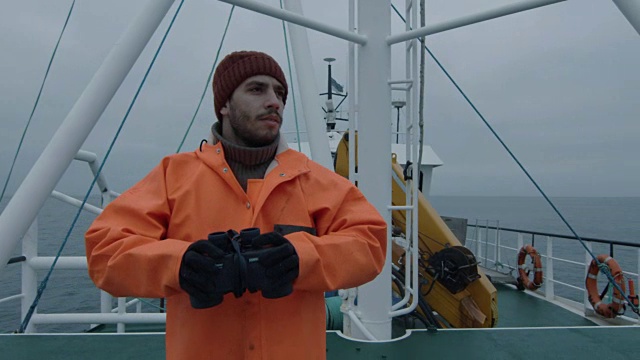 穿着防护服的商业渔船船长透过望远镜看视频素材