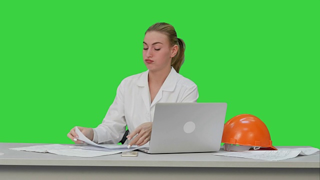 疲惫的年轻女子在安全帽打哈欠，并试图在绿色屏幕上工作，色度钥匙视频素材