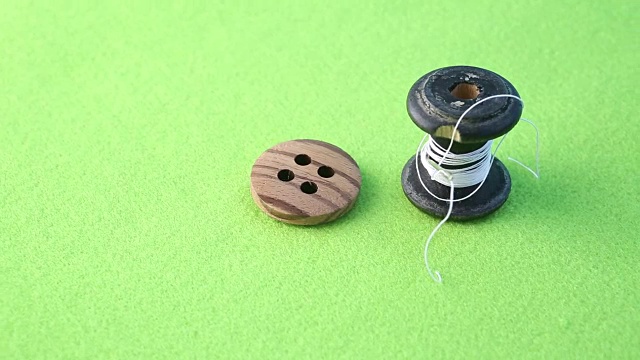 带钮和针的纱线卷在旋转的绿台上视频素材