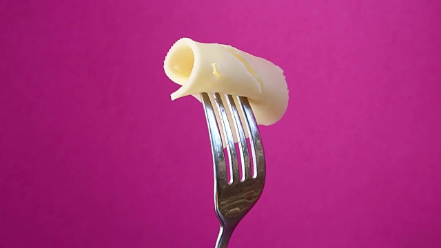 旋转的叉子和一片奶酪在紫色的背景视频素材