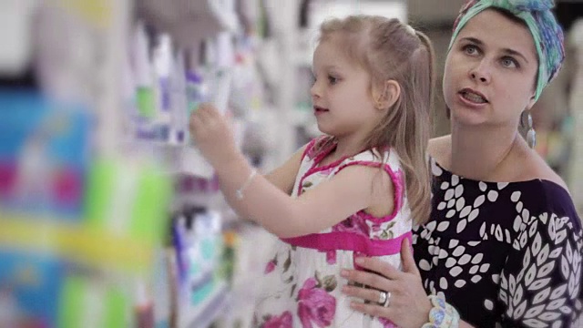 年轻女子与女儿在超市购买身体护理产品视频素材