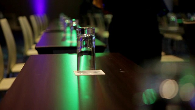 在会议厅的桌子和红椅子上放着装有水的瓶子和白床单视频下载