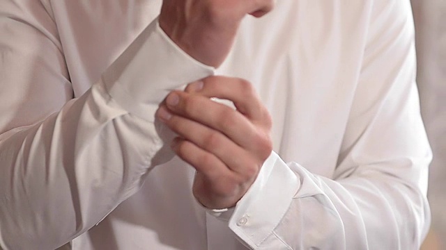 男人系好白衬衫袖子上的扣子，男人穿上白衬衫。视频下载