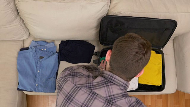 俯视图时间推移的人打包衣服到一个手提箱视频素材