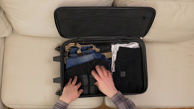 俯视图男性的手整理衣服和准备手提箱旅行视频素材