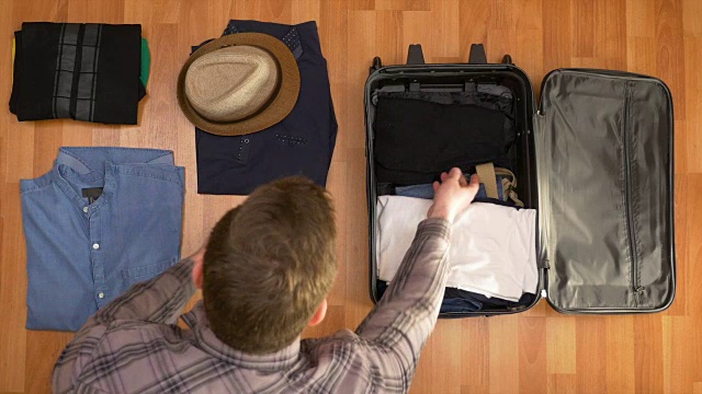 俯视图旅行概念的男人整理衣服到手提箱视频素材