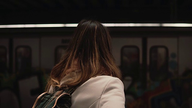 年轻女子背着背包站在火车站、地铁上。女孩在地铁里看着即将离开的火车视频素材