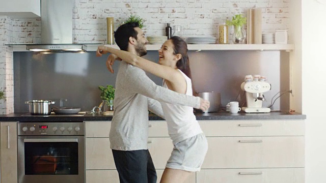 厨房里的幸福夫妻。女孩跳进男孩的怀抱。视频素材