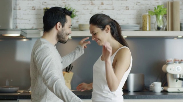 快乐的年轻夫妇在厨房跳舞，然后拥抱。在缓慢的运动。视频素材