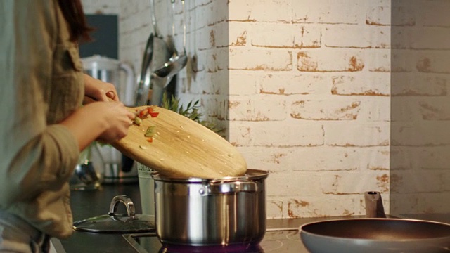 一个女人切蔬菜并把它们扔进蒸笼的特写镜头。视频素材