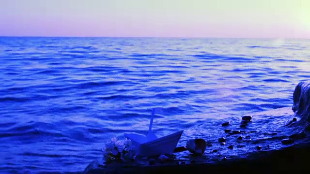 纸船、贝壳和一枝樱花在海边录影。视频素材