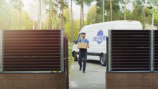 微笑的快递员带着包裹向房子走来。货车和阳光秋天与黄桦树和松树的背景。视频素材