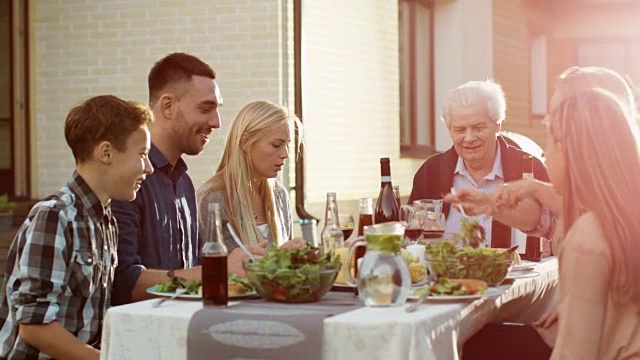 一群混合种族的人有乐趣，交流和吃在户外家庭晚餐视频素材