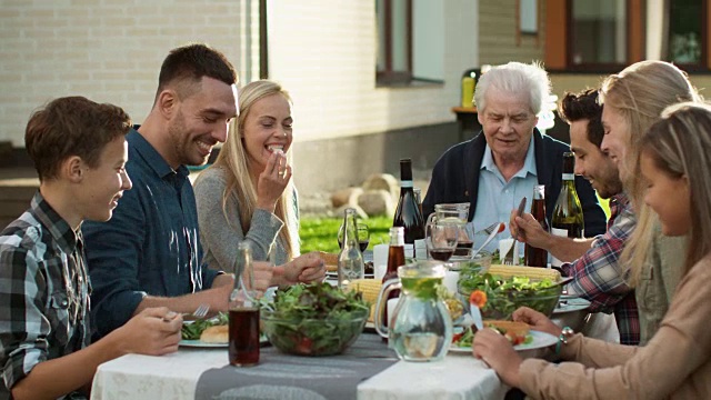 一群混合种族的人有乐趣，交流和吃在户外家庭晚餐视频素材