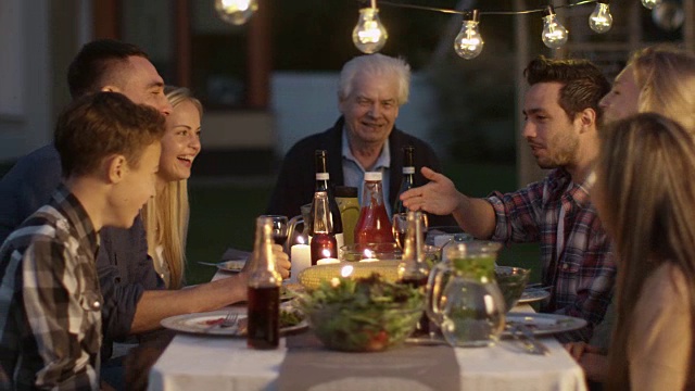 一群人围坐在一张桌子上，吃，交流和享受家庭聚餐视频素材