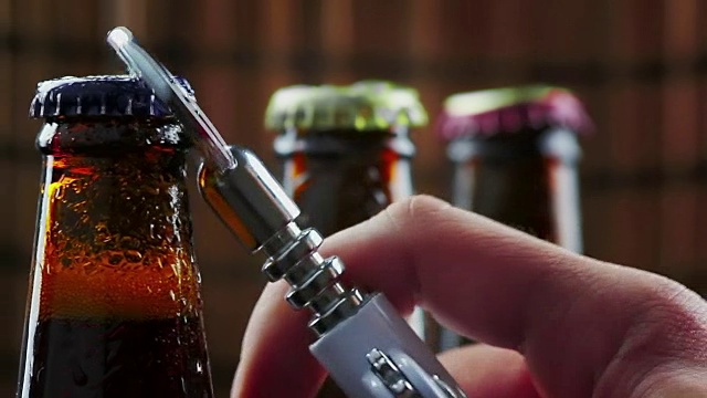 男子打开三瓶带泡沫的新鲜啤酒的瓶盖，在黑暗的酒吧背景下滴酒视频素材