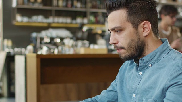 西班牙裔年轻人在舒适咖啡店使用笔记本电脑。视频素材