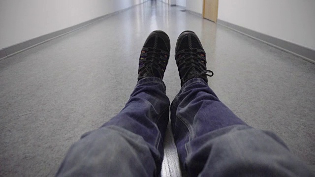 在一条长长的白色走廊里，有一双奇怪的脚坐在地板上视频下载
