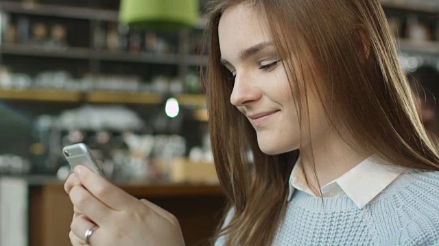 迷人的年轻女子在舒适咖啡馆使用手机。视频素材