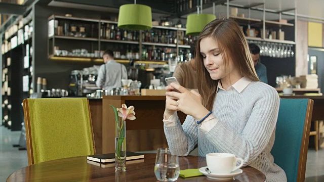迷人的年轻女子在舒适咖啡馆使用手机。视频素材