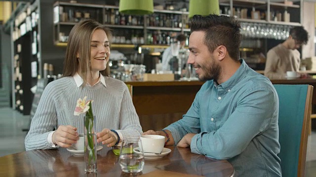 迷人的年轻男子和女子坐在舒适的咖啡店聊天。视频素材