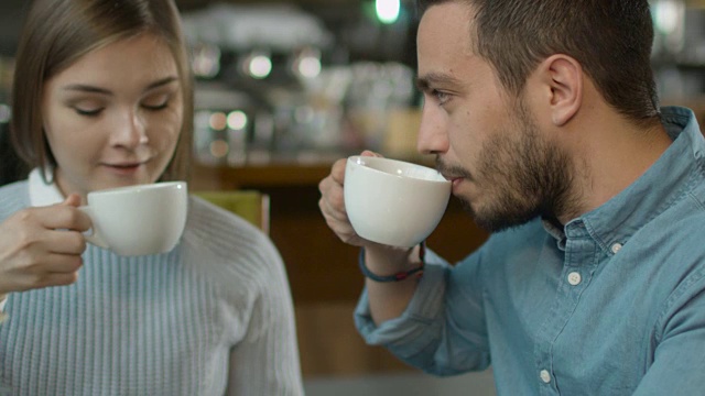 迷人的年轻男子和女子坐在舒适的咖啡店聊天。视频素材