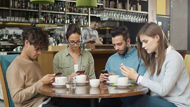 一群年轻的混血儿在咖啡店里使用手机。视频素材