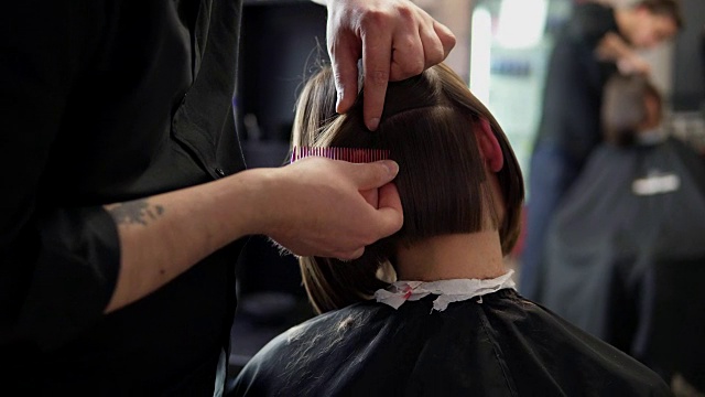 一个理发师在专业发廊剪头发的年轻女子的特写。美容护发理念。在4 k拍摄视频下载