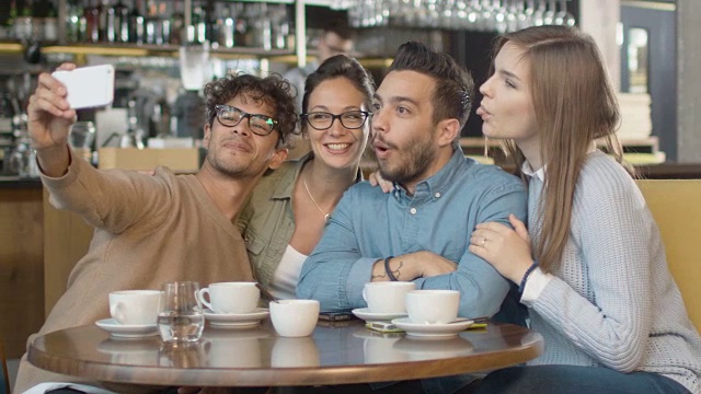 一群年轻的混血儿微笑着在咖啡店用手机自拍。视频素材