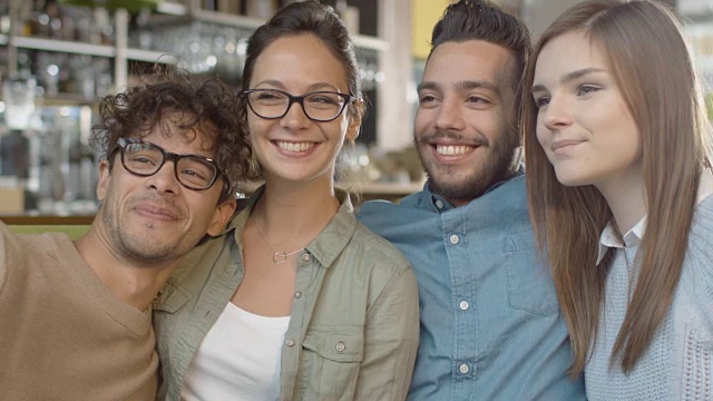 一群年轻的混血儿微笑着在咖啡店用手机自拍。视频素材