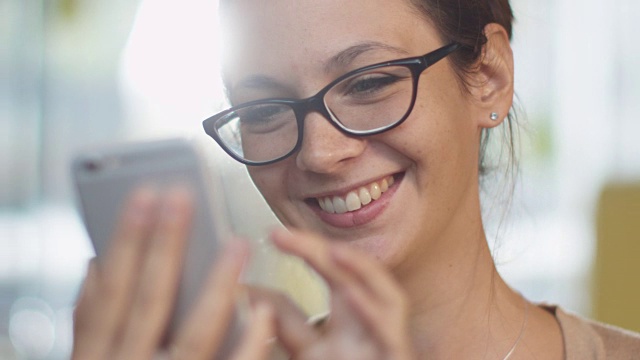 白人微笑的年轻女子在舒适咖啡馆使用手机。视频素材
