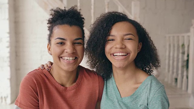 特写的两个美丽的非洲裔美国女孩笑着看着相机。女人在家里从严肃的表情到大笑都会表现出情绪视频素材