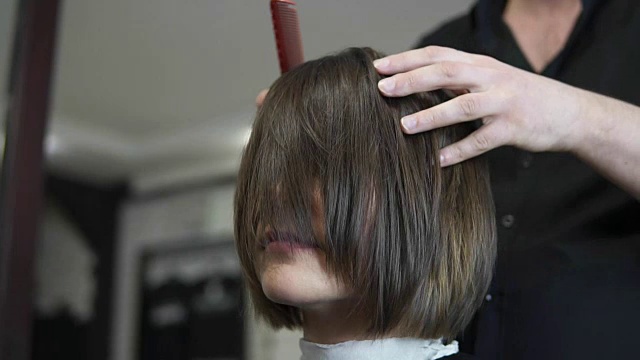 专业美发师在理发后使用刷子。年轻女子在美发沙龙做头发。发型师用吹风机。理发师在起作用。美容沙龙。在slowmotion拍摄视频下载