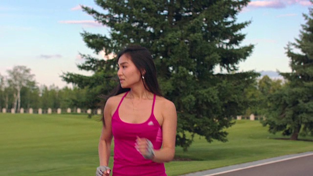 在公园里跑步的亚洲女人。健身女人在户外跑步的特写视频素材