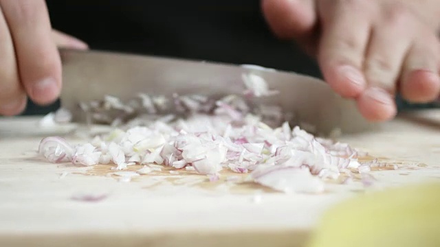 前视图的年青人煮红洋葱切薄片用刀切板。视频素材