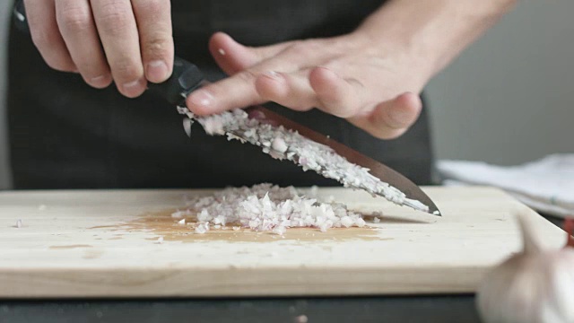 前视图的年青人煮红洋葱切薄片用刀切板。视频素材