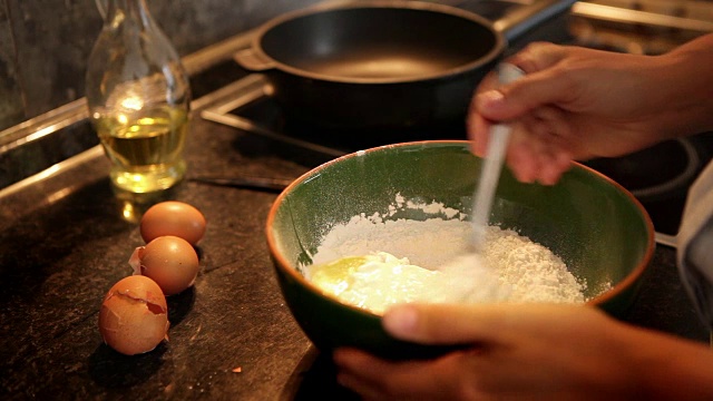 慢镜头:一名厨师将乳制品与面粉和鸡蛋一起放入碗中做成面团视频下载