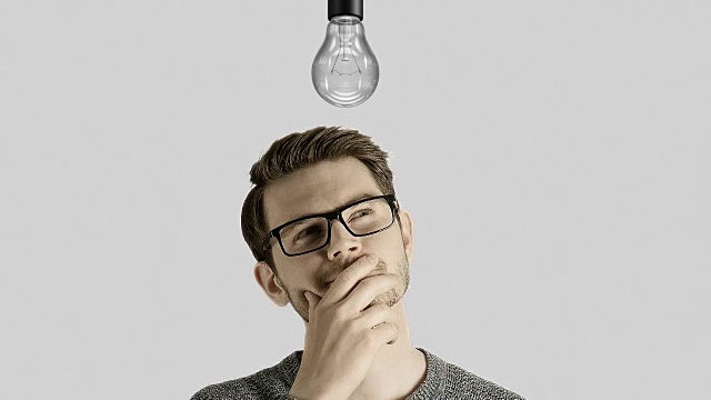 聪明有创意的人想到了一个主意，在白色的背景下，他的头上点亮了一盏象征性的灯视频素材