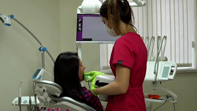 年轻女牙医使用手提设备进行颌部x光检查。在4 k拍摄视频素材