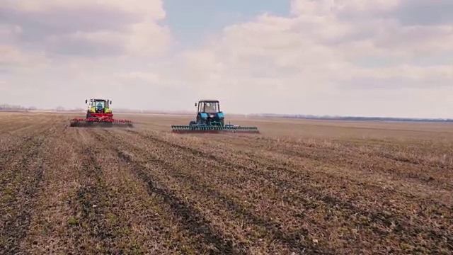 斯坦尼康镜头:两辆拖拉机在田地上前进，耕种土地视频下载