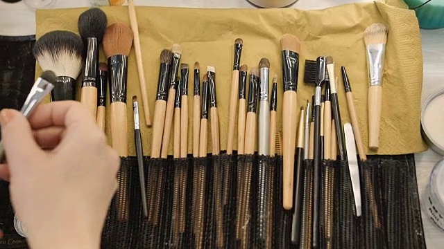 化妆师从专业的画笔组拿画笔。美容、化妆和时尚概念视频下载