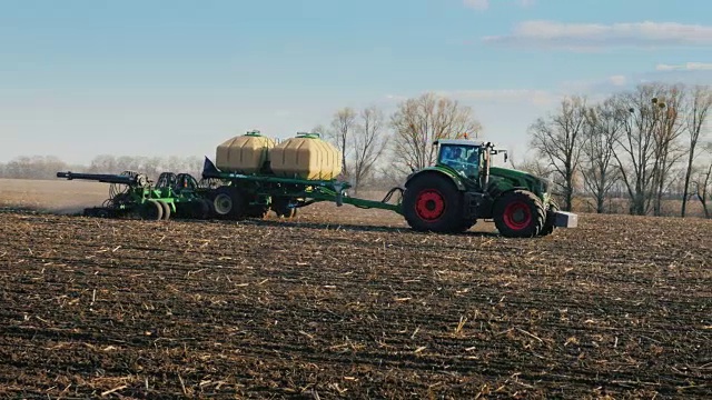 斯坦尼康盘拍摄:拖拉机与播种机播种小麦在田间在早春。侧视图视频素材